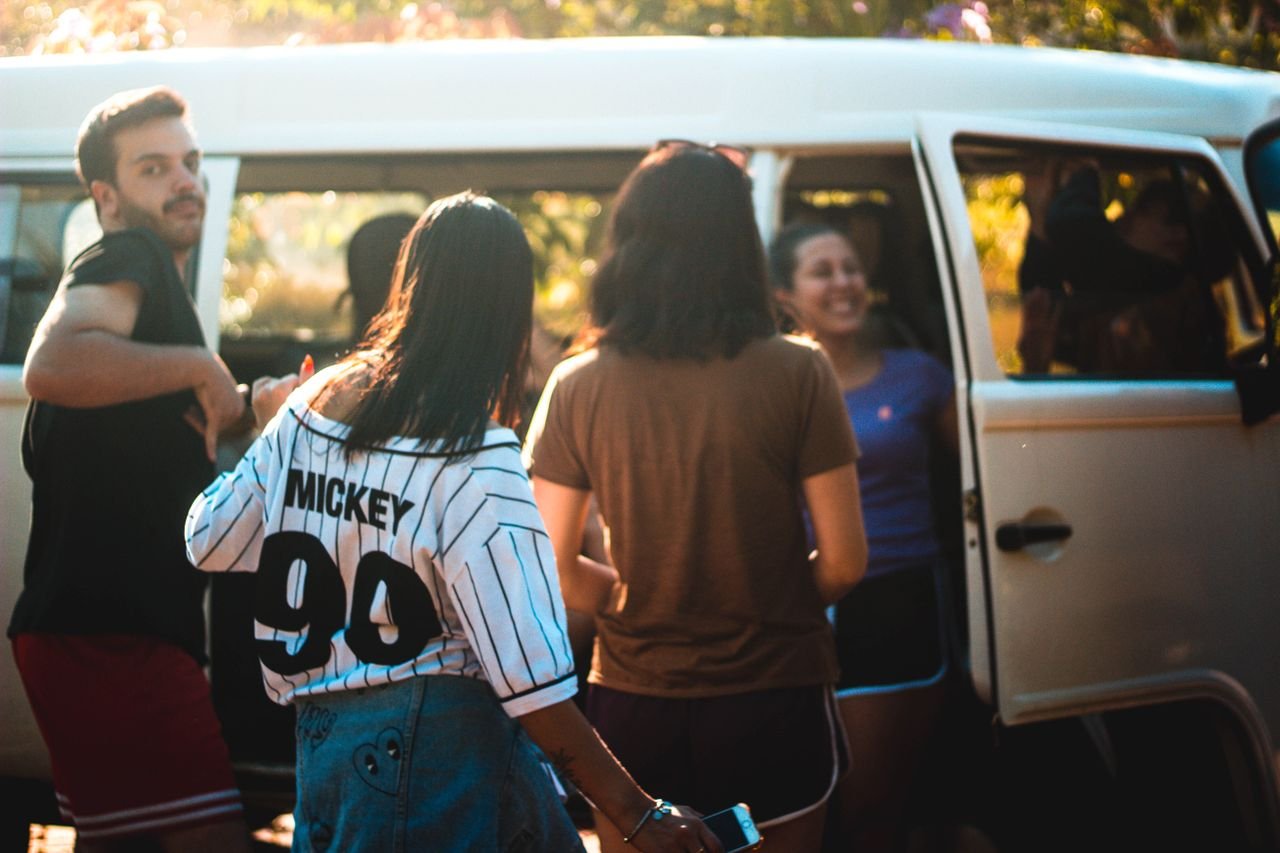 Group of young adults enjoying a sunny day, gathering near a van.